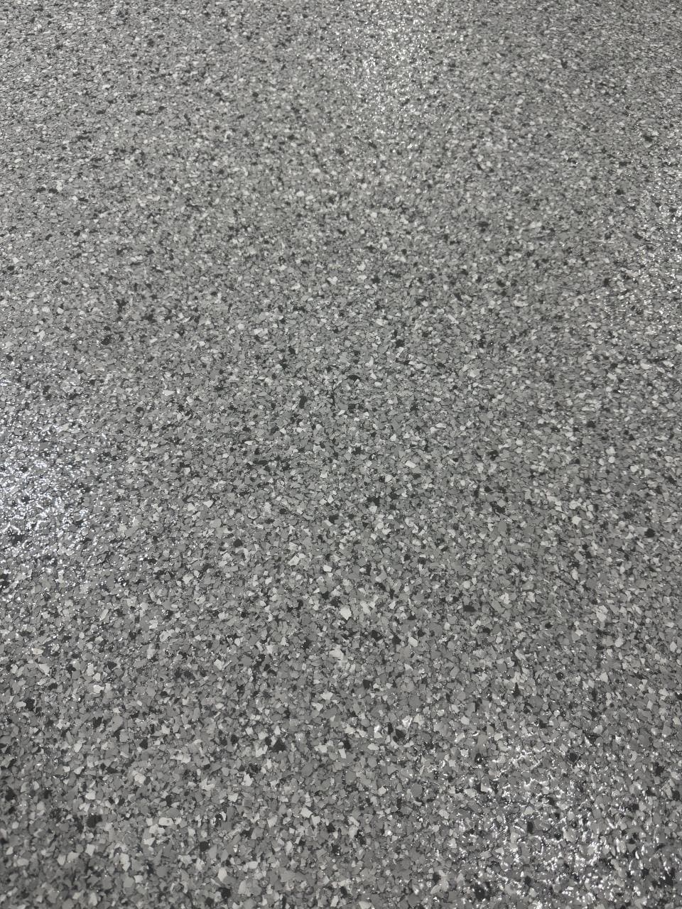 Close up of a gray and white flake floor finish suitable for a basement