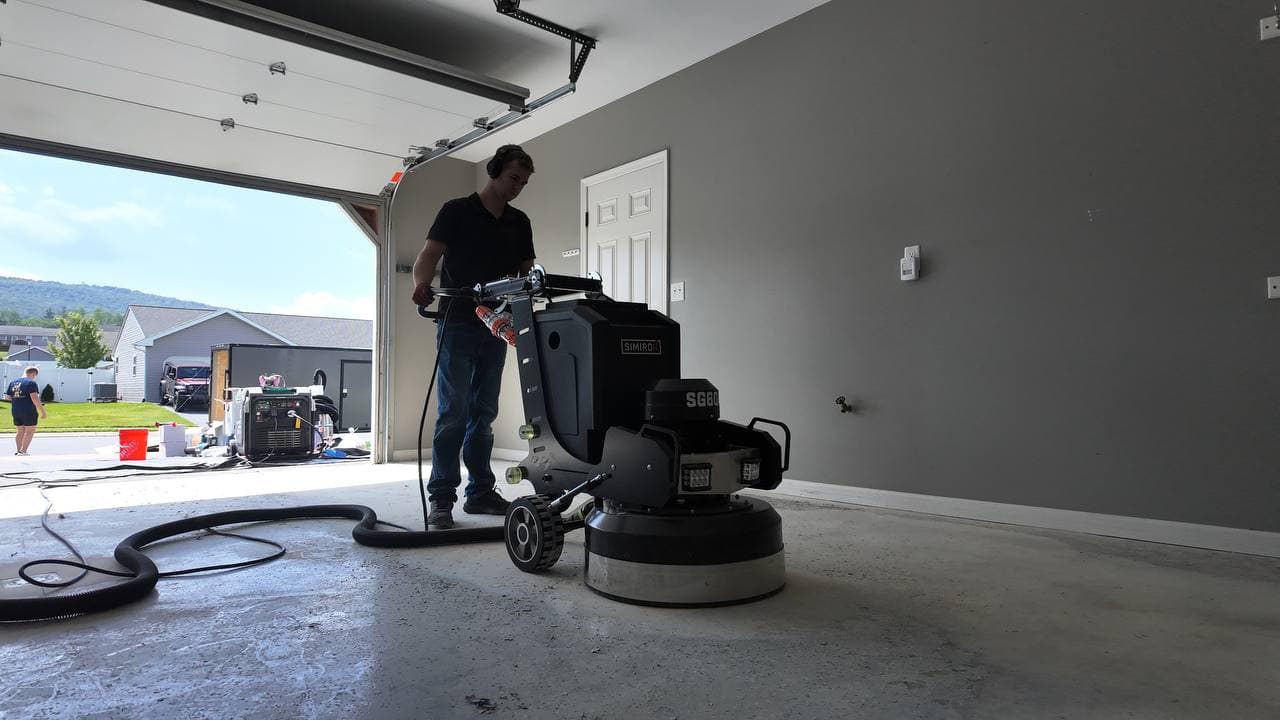 Crew grinding a garage slab with a dust extractor running