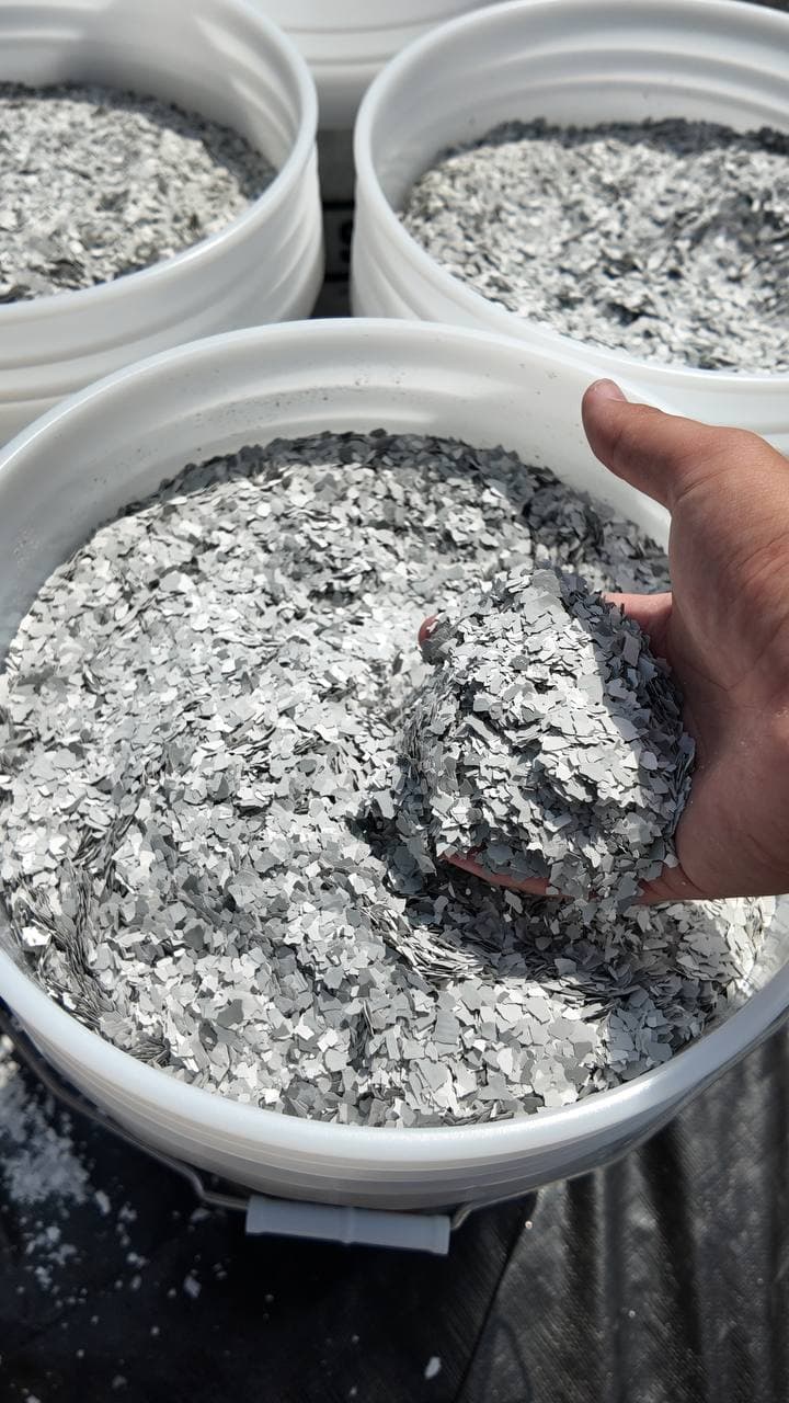 Handful of vinyl flake lifted from a mixing bucket on site